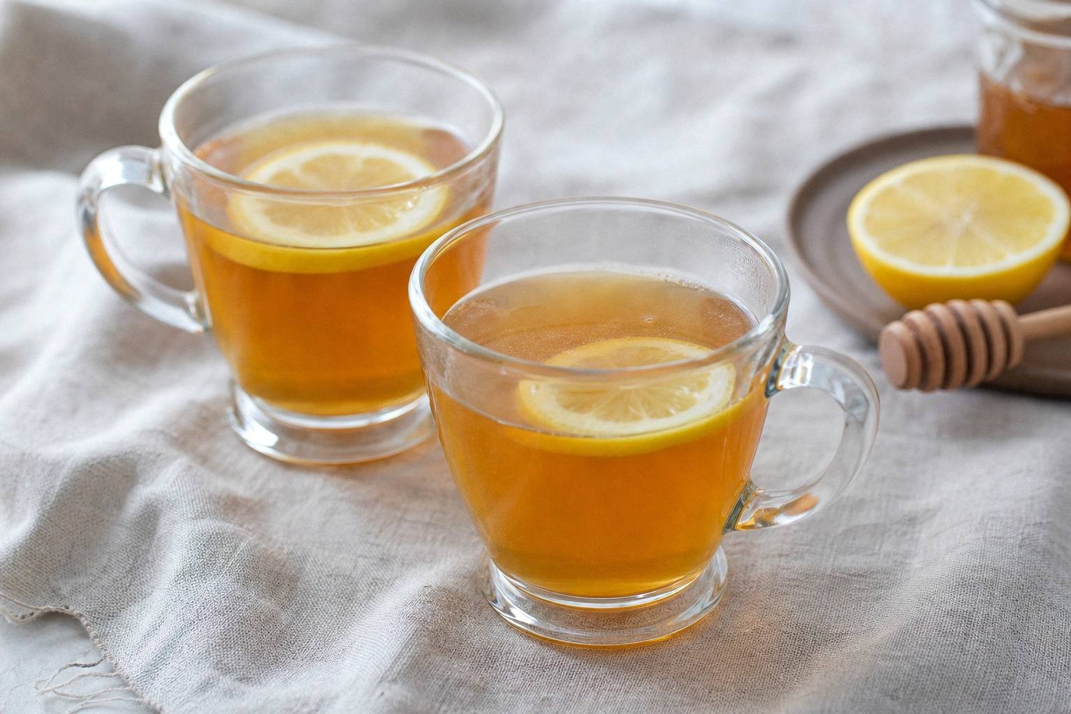 two hot toddies in mugs on wooden table with lemon slices, styled for serving