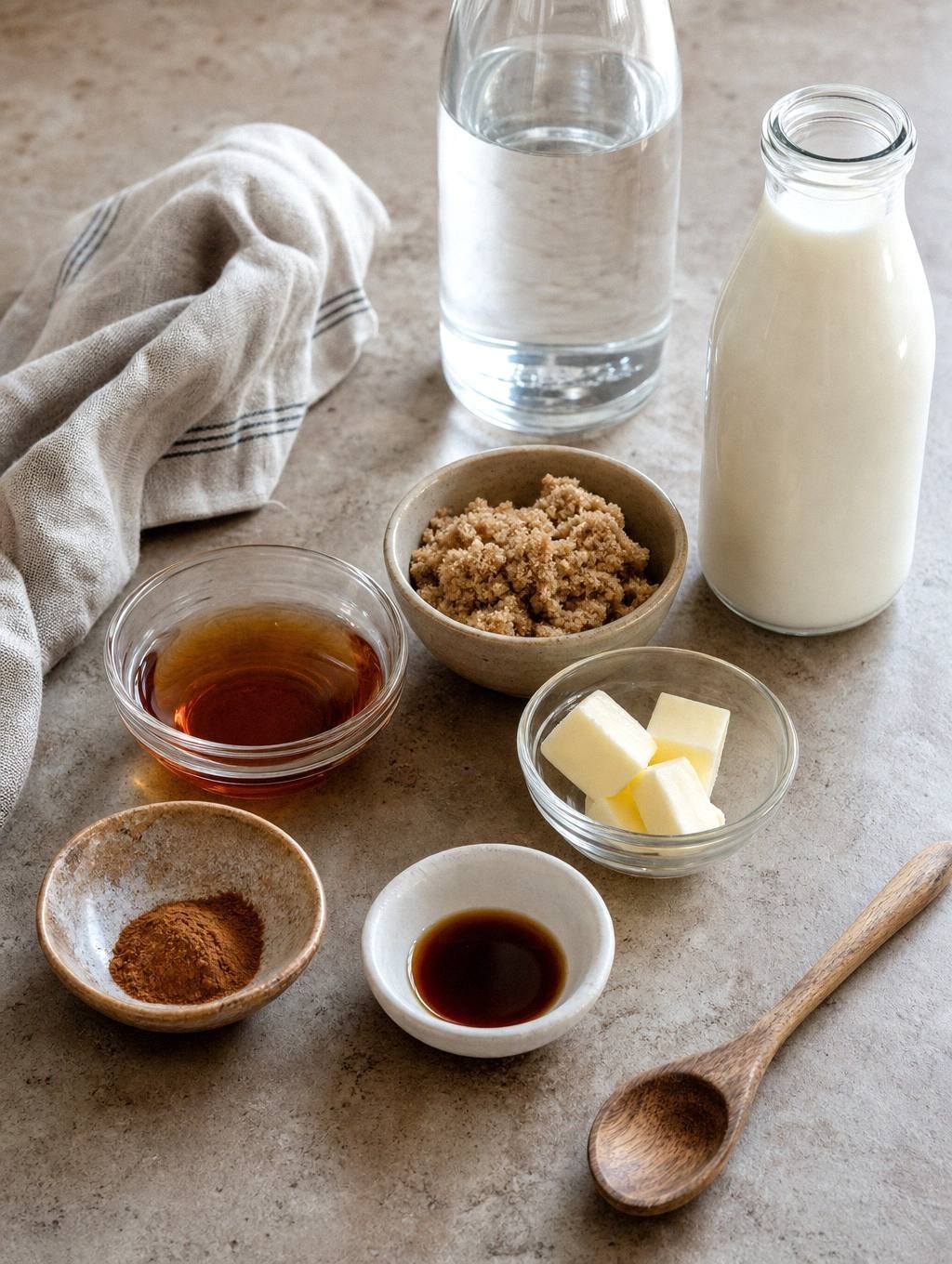 ingredients for french toast iced latte measured in small bowls including maple syrup, brown sugar, cinnamon, and milk